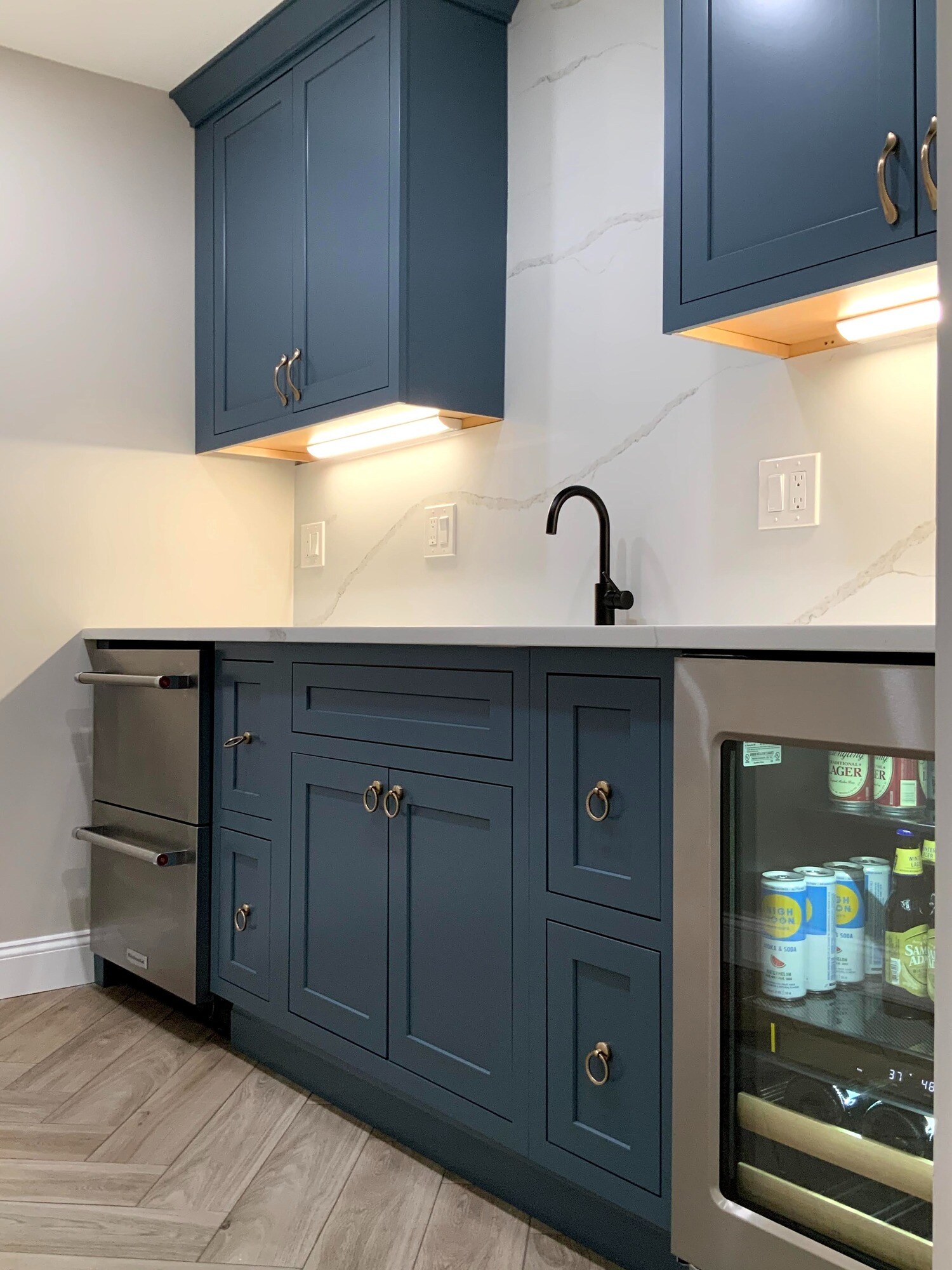 wet bar in finished basement with blue cabinets