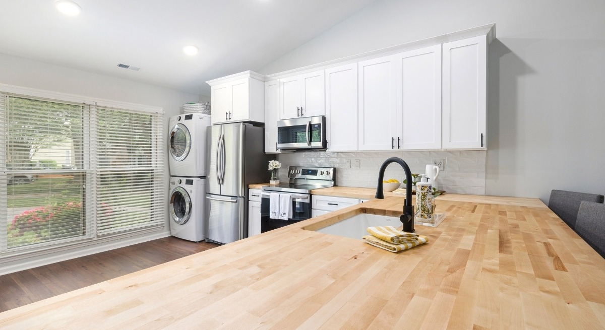 Bright Boston area kitchen adu with wood counters, white cabinets, and stacked washer-dryer unit-1