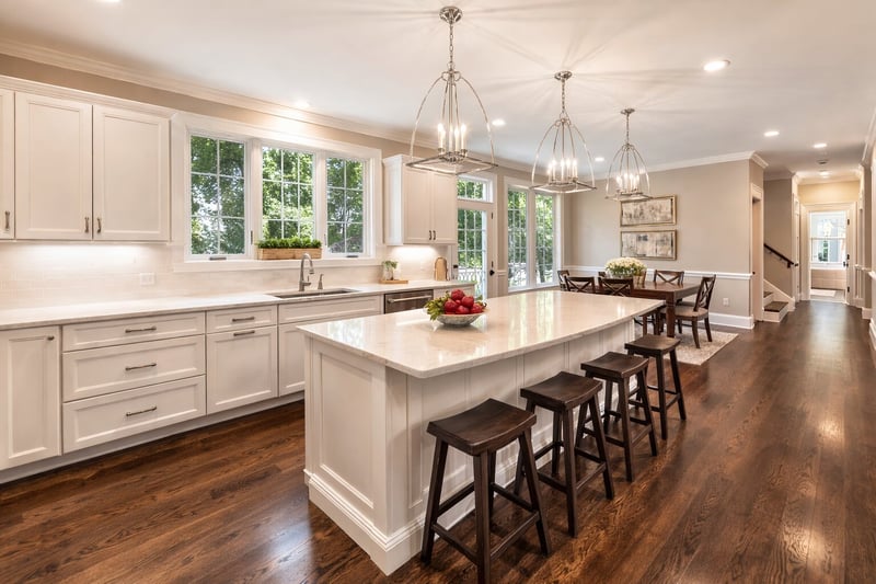 Bright open-concept kitchen with white cabinets, large island, and wood floors in Greater Boston home