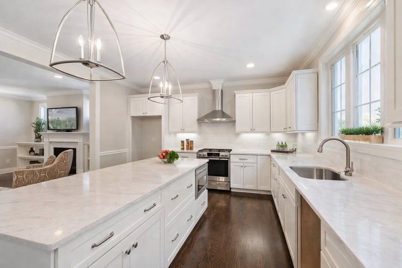 Bright white kitchen with large island, marble countertops, and modern pendant lighting, located in an Arlington custom home