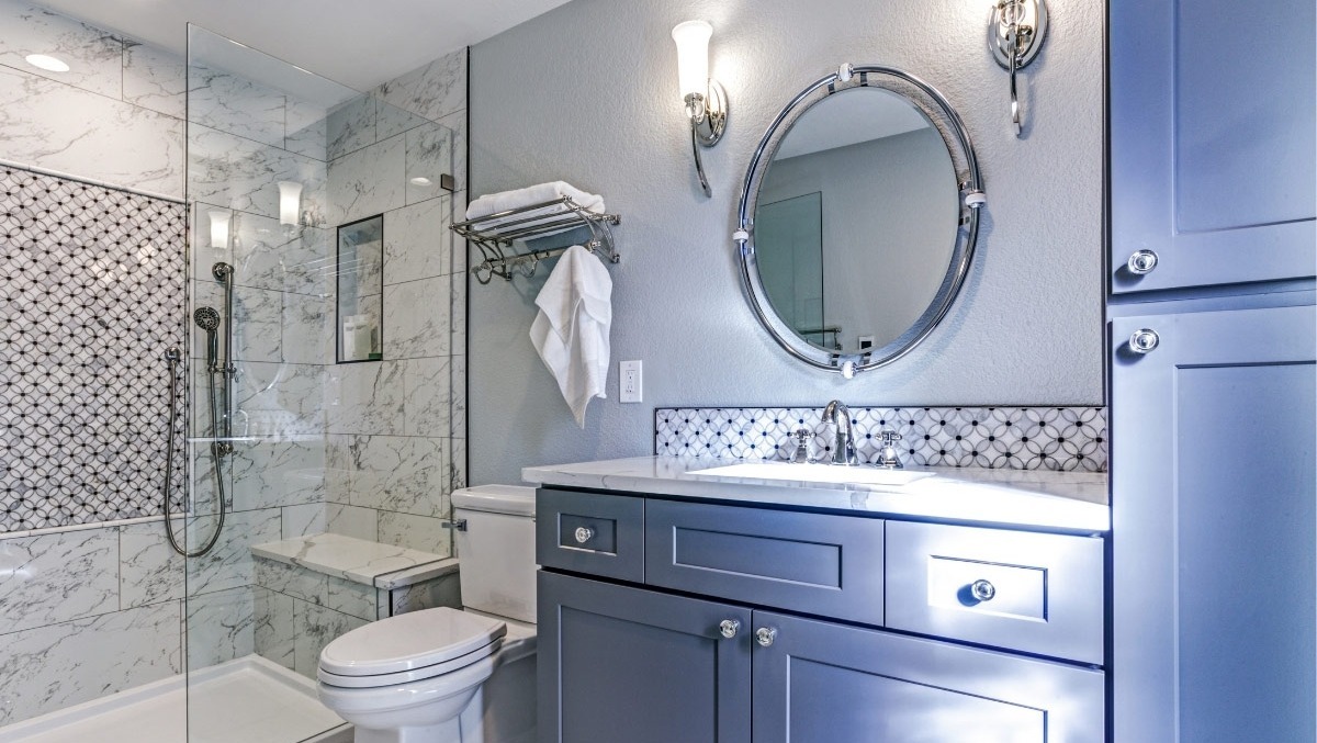 Elegant Boston-area adu bathroom with gray cabinets, glass shower, and patterned tile accents