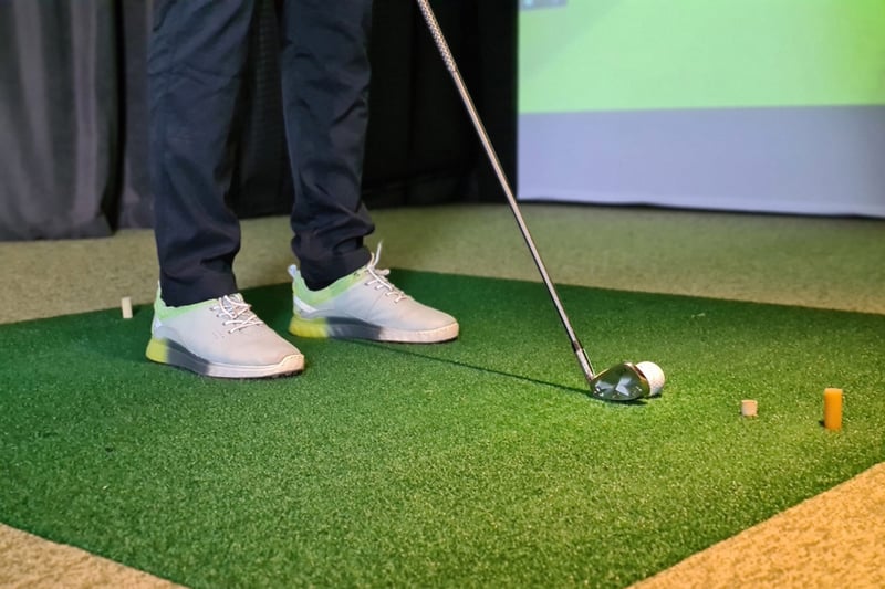Golfer lining up a shot on indoor turf in the Greater Boston area golf simulator