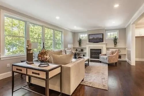 Greater Boston living room with fireplace, built-ins, large windows and neutral seating on dark hardwood floors