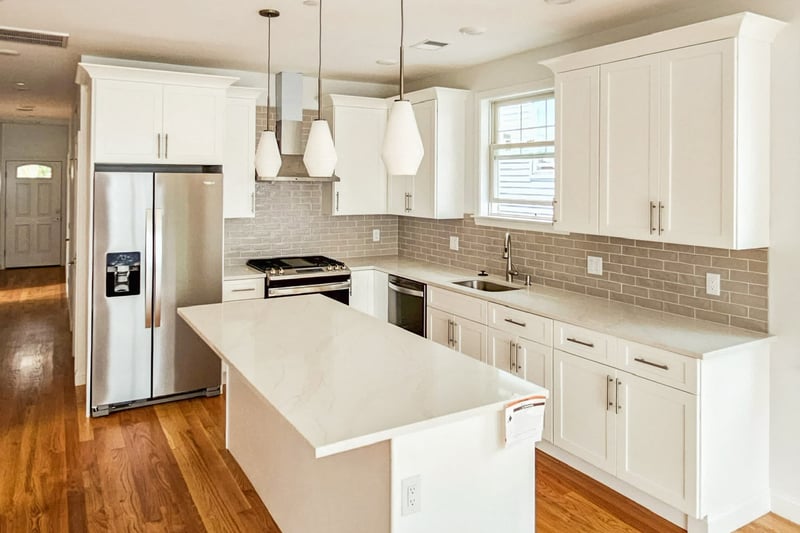 Modern Greater Boston area kitchen with white cabinets, quartz island, and stainless appliances