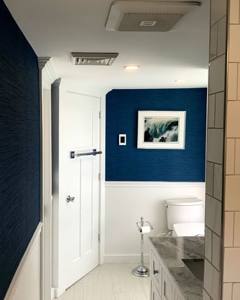 Modern bathroom with navy accent wall and white wainscoting in the Boston area