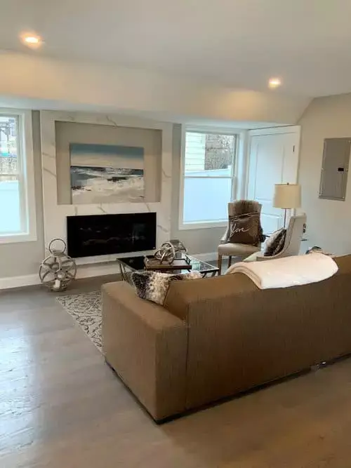 Contemporary living room with sofa seating, fireplace, large windows, and neutral décor inside a modern condo in Greater Boston