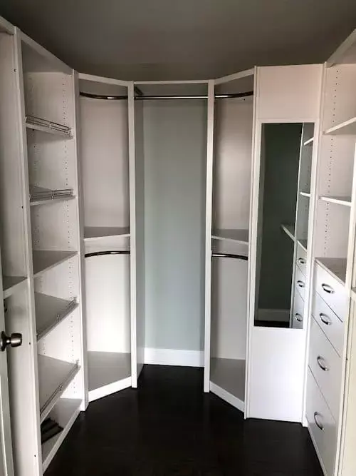 Custom walk-in closet with white shelving, drawers, hanging space, and built-in mirror storage inside a modern home in Greater Boston