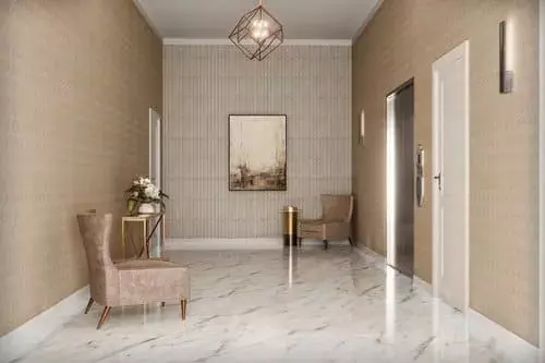 Modern apartment lobby with marble floors, beige walls, seating, artwork, and elevator access in a residential building in Greater Boston
