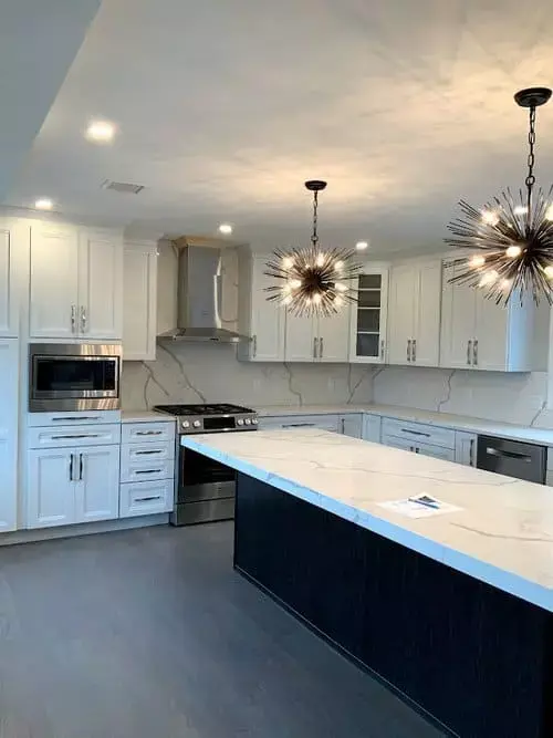Modern kitchen with white cabinetry, marble backsplash, large island, stainless appliances, and starburst pendant lights in a home in Greater Boston