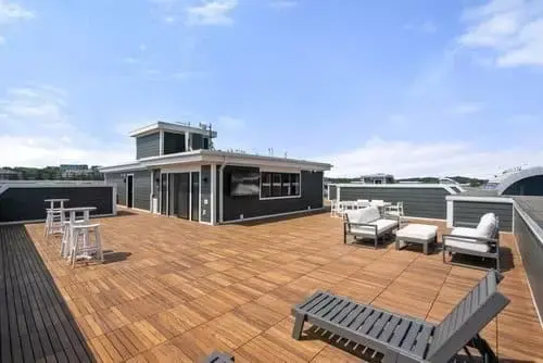 Rooftop deck with wood flooring, lounge seating, bar stools, and city views on a modern home in Greater Boston