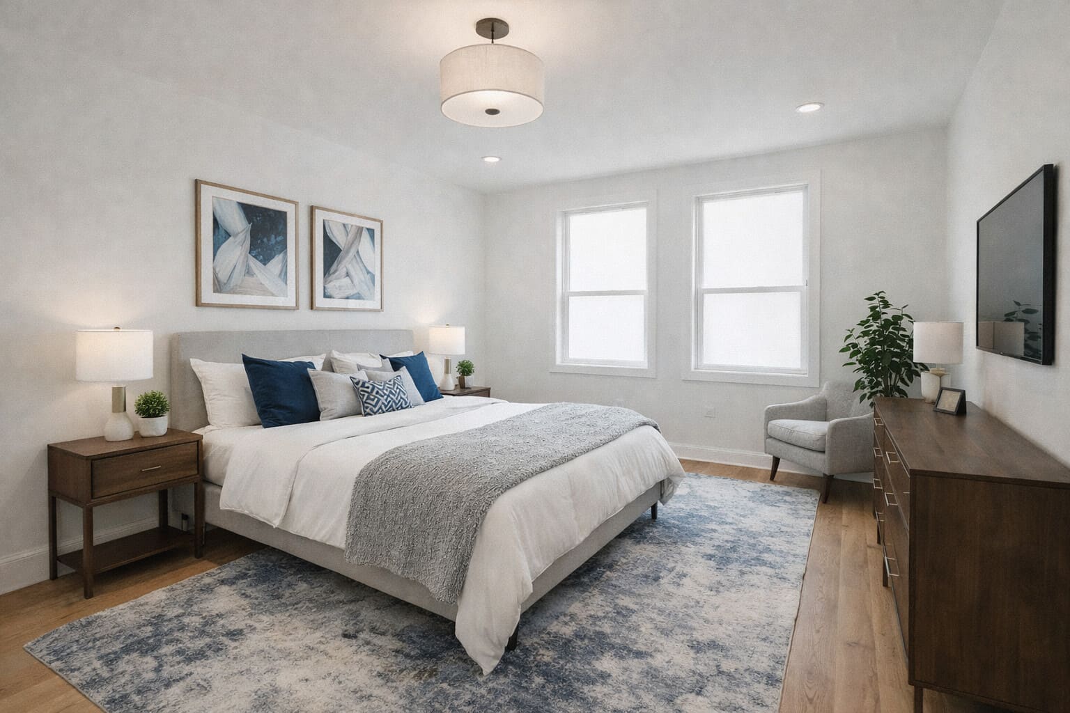 Bright primary bedroom with upholstered bed, blue accents, hardwood floors, and modern decor, located in the Greater Boston area